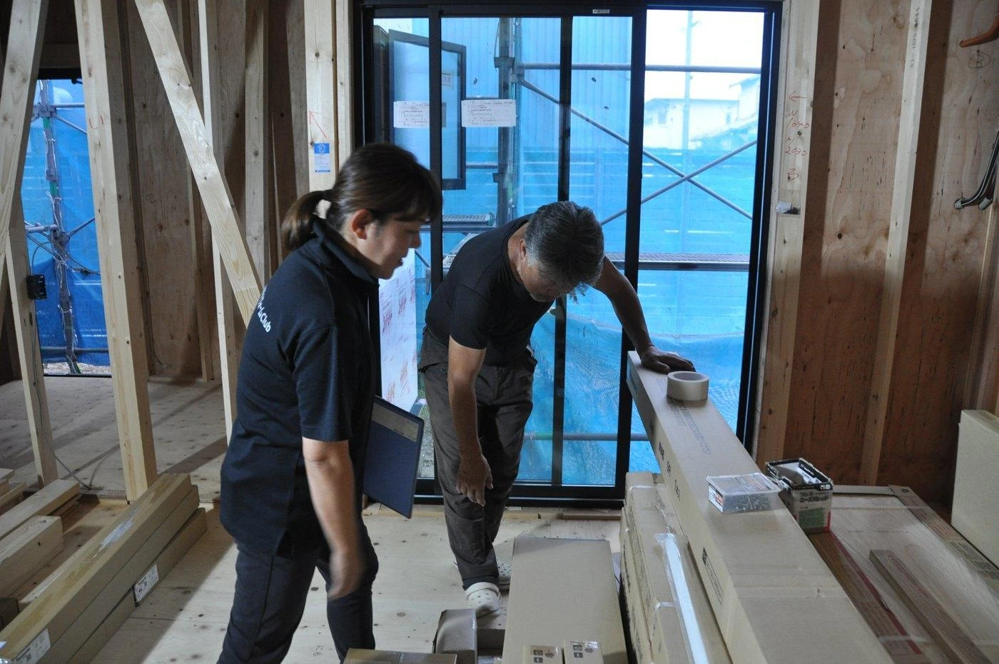 現場で建材と納まりを確認するカインドのスタッフと職人