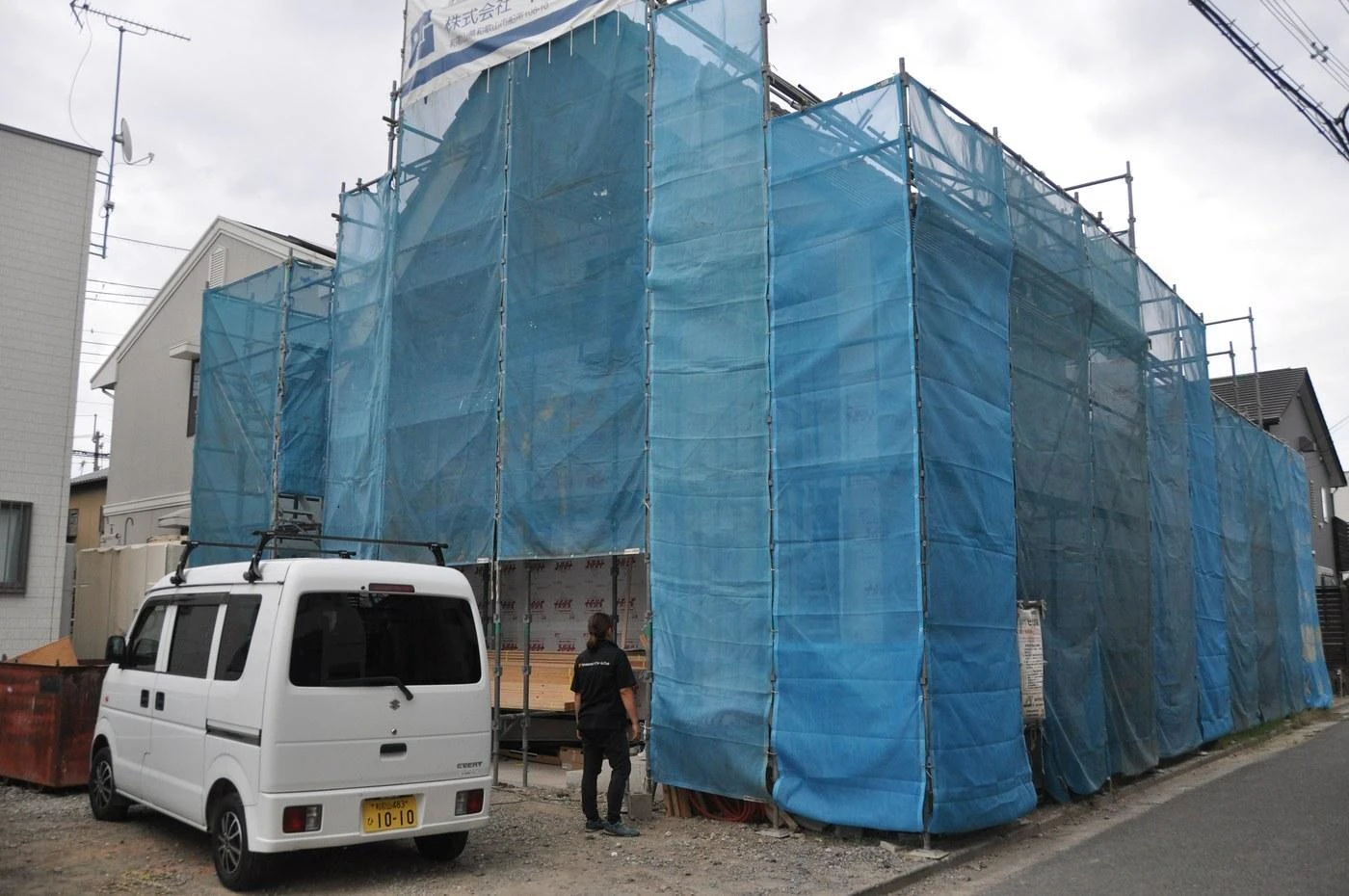 外まわりの工事にあわせて足場を組み、メッシュシートで覆った住まい